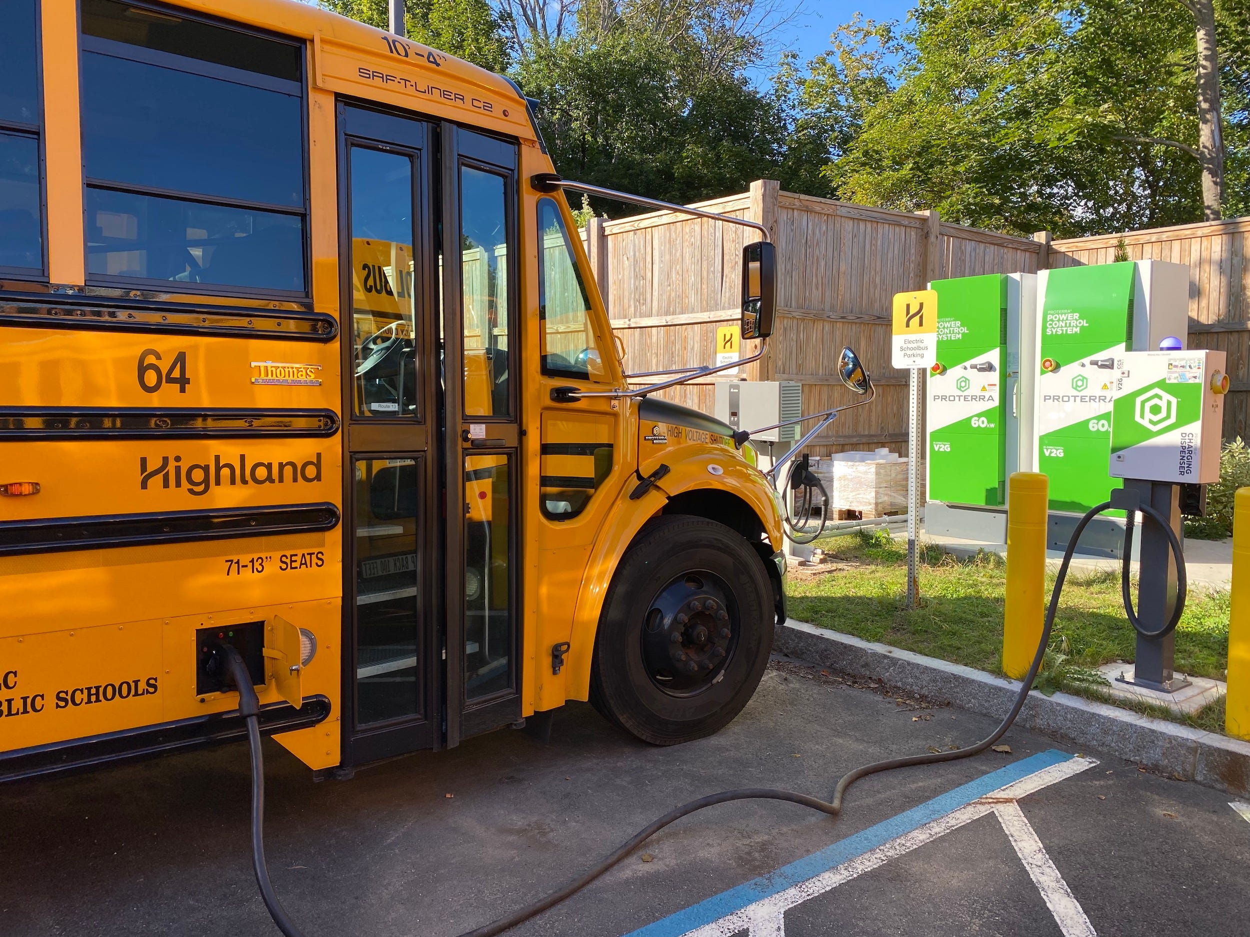 An electric school bus from Highland Electric Fleets plugged into a charger.