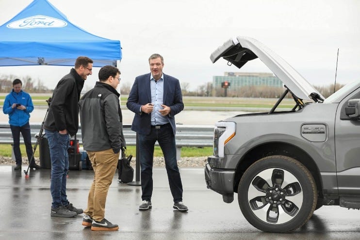 Darren Palmer speaks with customers in front of a Ford F-150 Lightning with its trunk open.